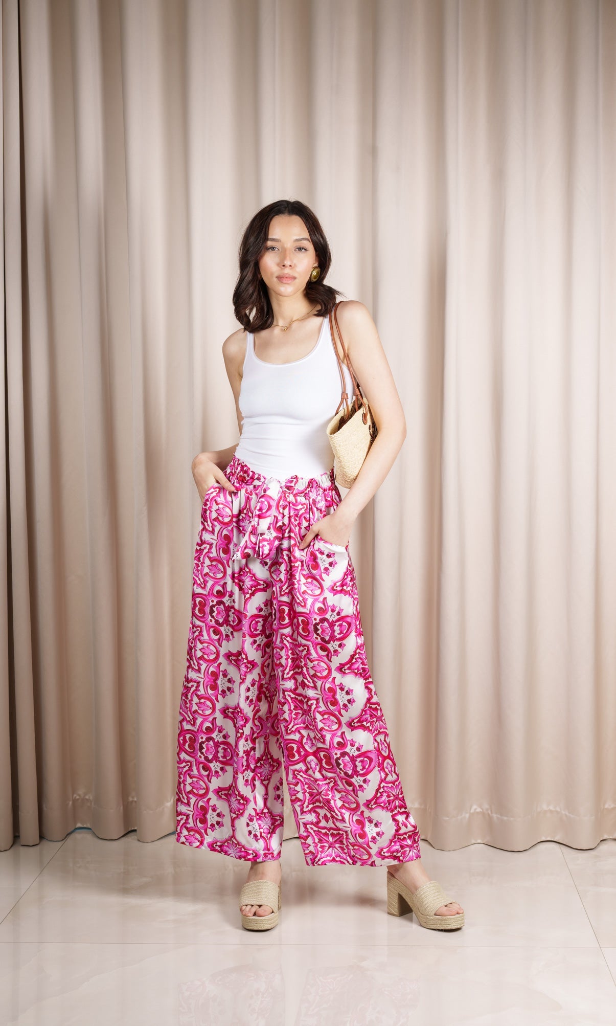 Model wears pants in a silk blend adorned with a captivating print in delicate shades of pink and white