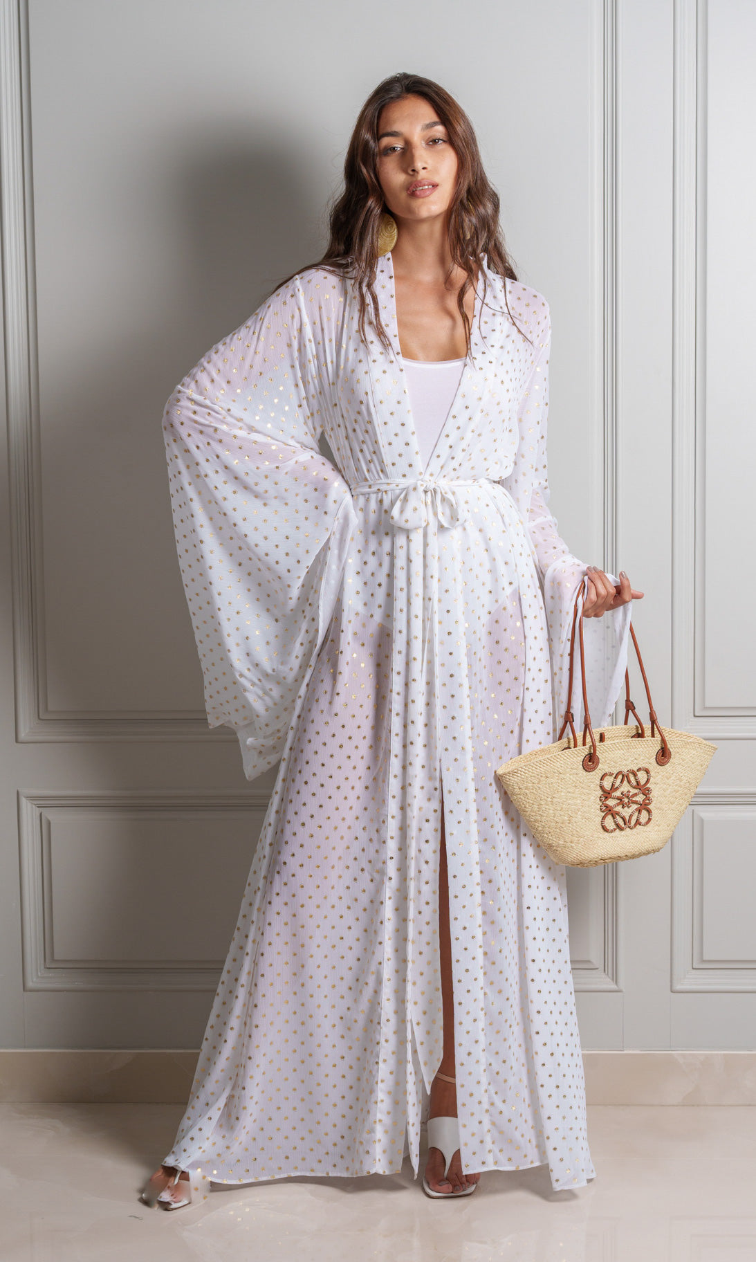 Model wears opulent white kimono crafted from a luxurious chiffon fabric with gold polka dot detailing