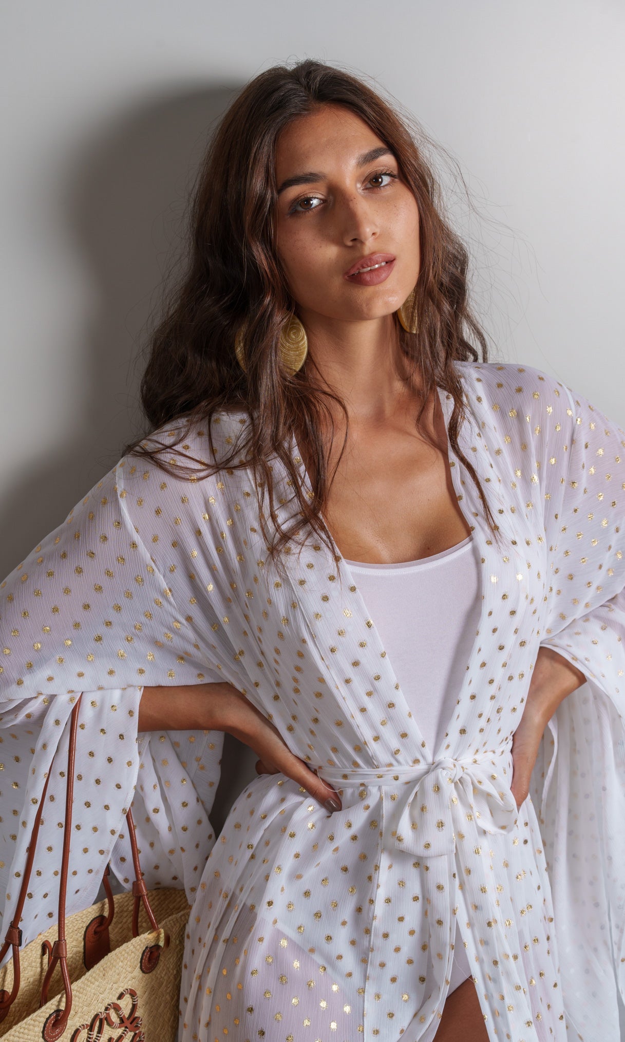 Model wears opulent white kimono crafted from a luxurious chiffon fabric with gold polka dot detailing